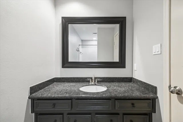 a bathroom with a granite countertop sink and a mirror