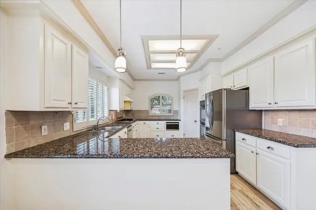 a kitchen with stainless steel appliances granite countertop a sink a stove a refrigerator a center island a counter space and cabinets