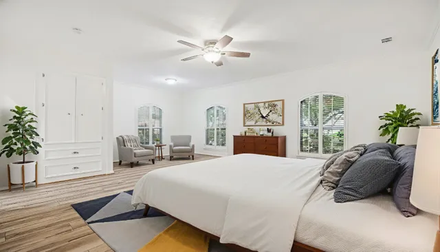a spacious bedroom with a bed a window and potted plant