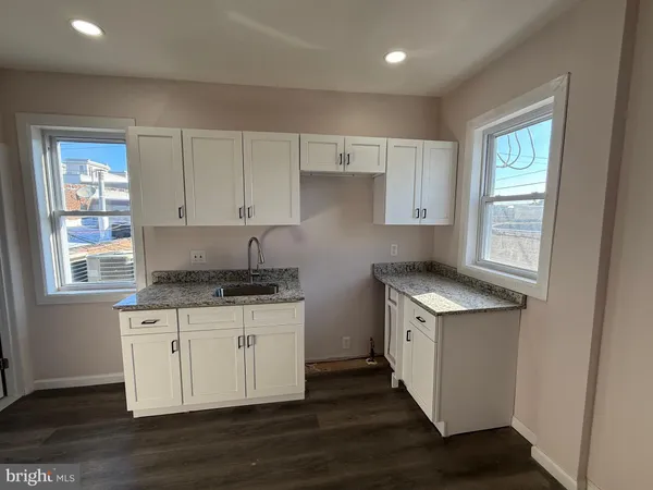 a kitchen with granite countertop a sink stove and cabinets