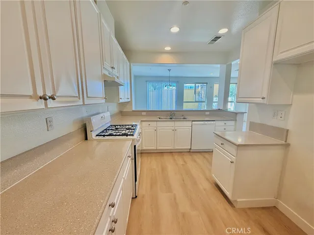 a kitchen with stainless steel appliances granite countertop a stove a sink and white cabinets