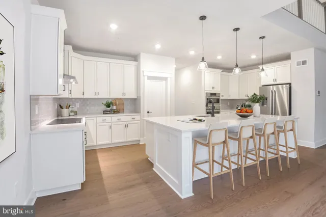 a kitchen that has a lot of white cabinets and stainless steel appliances