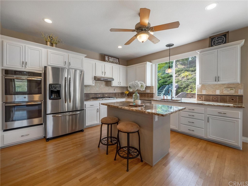 2 Whippoorwill Road Trabuco Canyon, CA 92679 - Photo 20 of 57 a kitchen with stainless steel appliances granite countertop a stove a refrigerator a sink a stove and white cabinets with wooden floor