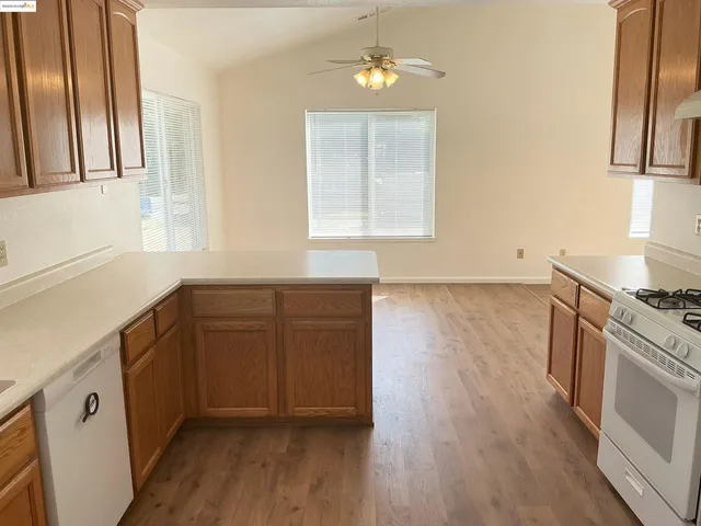 a kitchen with stainless steel appliances granite countertop a stove a sink and a refrigerator with wooden floors