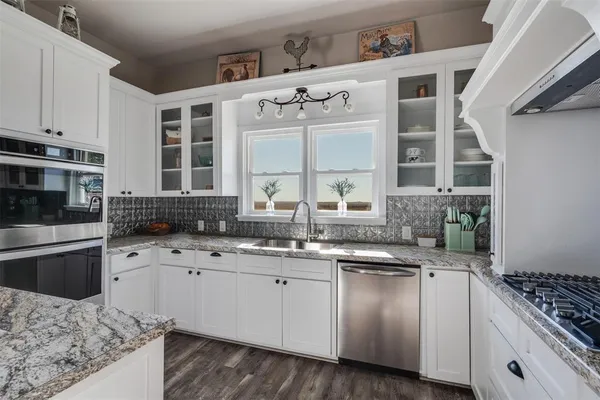 a kitchen with granite countertop a sink stainless steel appliances and cabinets