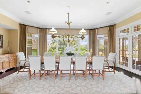 a dining room with wooden floor a chandelier a wooden table and chairs