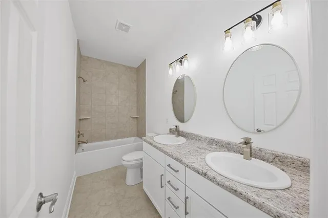a bathroom with a granite countertop sink a toilet and a mirror