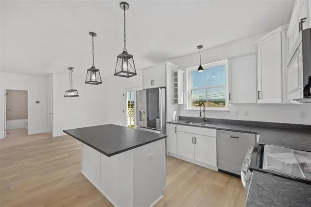 a kitchen with stainless steel appliances granite countertop a sink a stove and a wooden floors