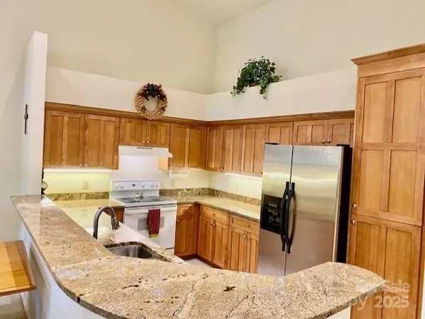 a kitchen with stainless steel appliances granite countertop a sink refrigerator and cabinets