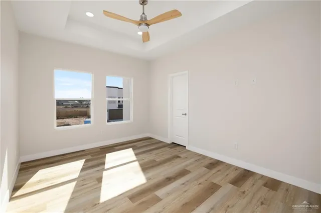 an empty room with wooden floor fan and windows