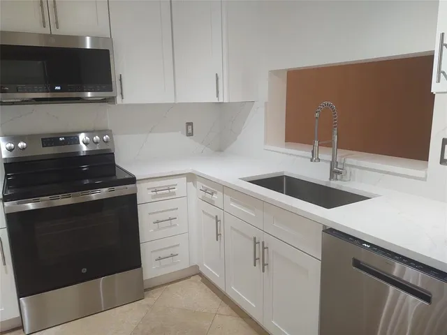 a kitchen with white cabinets and black appliances