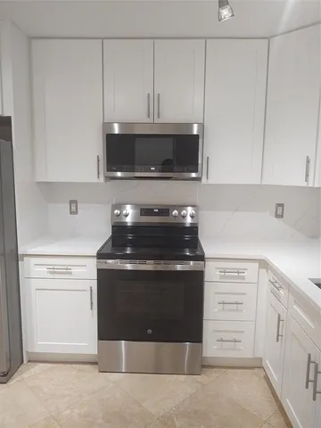 a kitchen with granite countertop white cabinets and stainless steel appliances