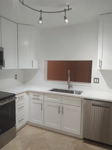 a kitchen with white cabinets sink and dishwasher