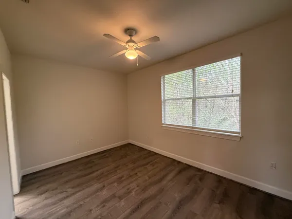 an empty room with wooden floor and a ceiling fan
