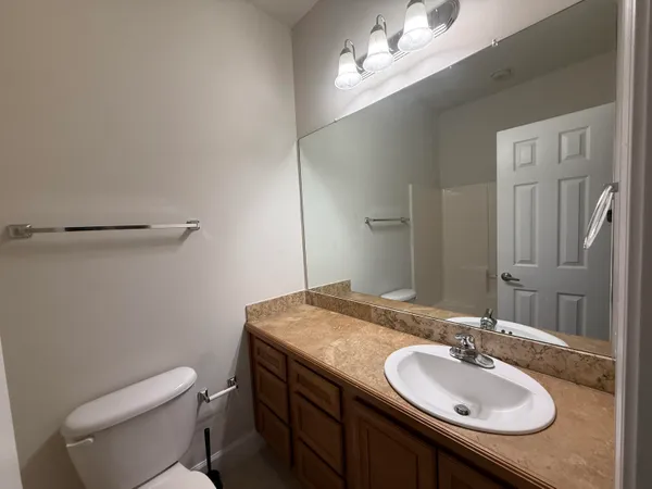 a bathroom with a granite countertop sink a toilet and a mirror
