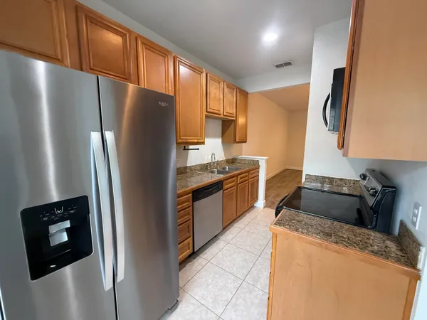 a kitchen with granite countertop stainless steel appliances a refrigerator a stove a microwave a sink and a refrigerator