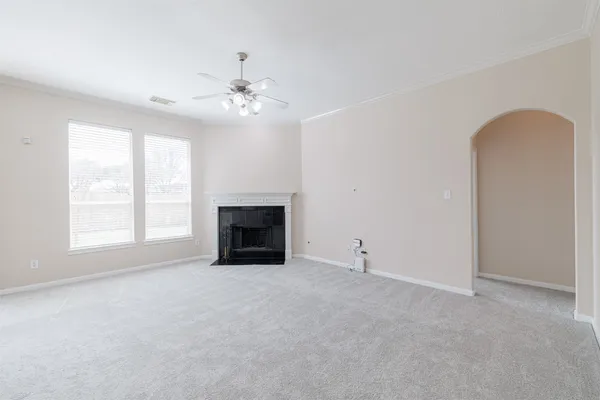 an empty room with windows and fireplace
