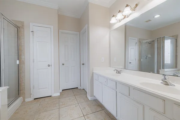 a spacious bathroom with a double vanity sink a mirror and a shower