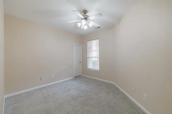 a view of an empty room with a chandelier fan