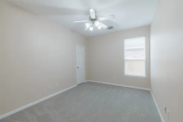 an empty room with a chandelier fan and windows