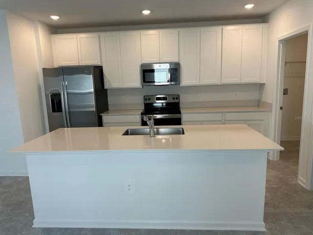 a kitchen with stainless steel appliances a refrigerator a stove a microwave and sink