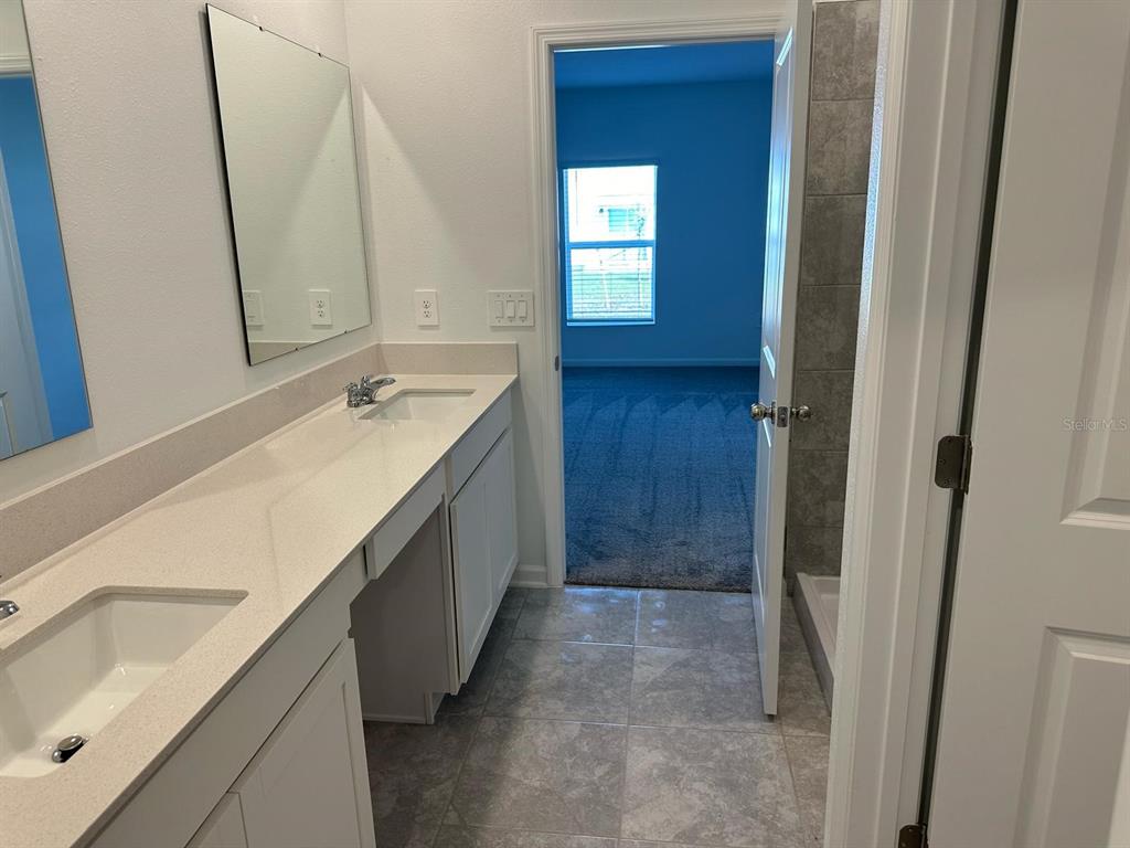 417 Cedar Key Street Davenport, FL 33837 - Photo 35 of 58 a bathroom with a sink a mirror and a shower