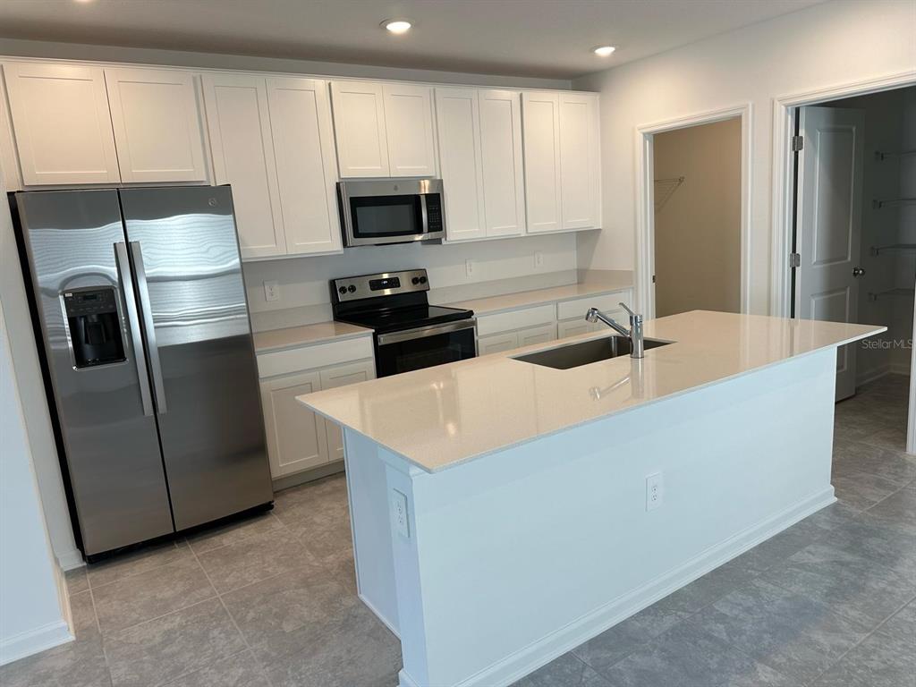 417 Cedar Key Street Davenport, FL 33837 - Photo 40 of 58 a kitchen with stainless steel appliances granite countertop a refrigerator a stove a sink and a microwave