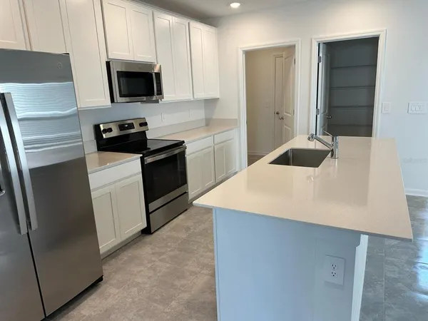 a kitchen with a sink a microwave a refrigerator and cabinets