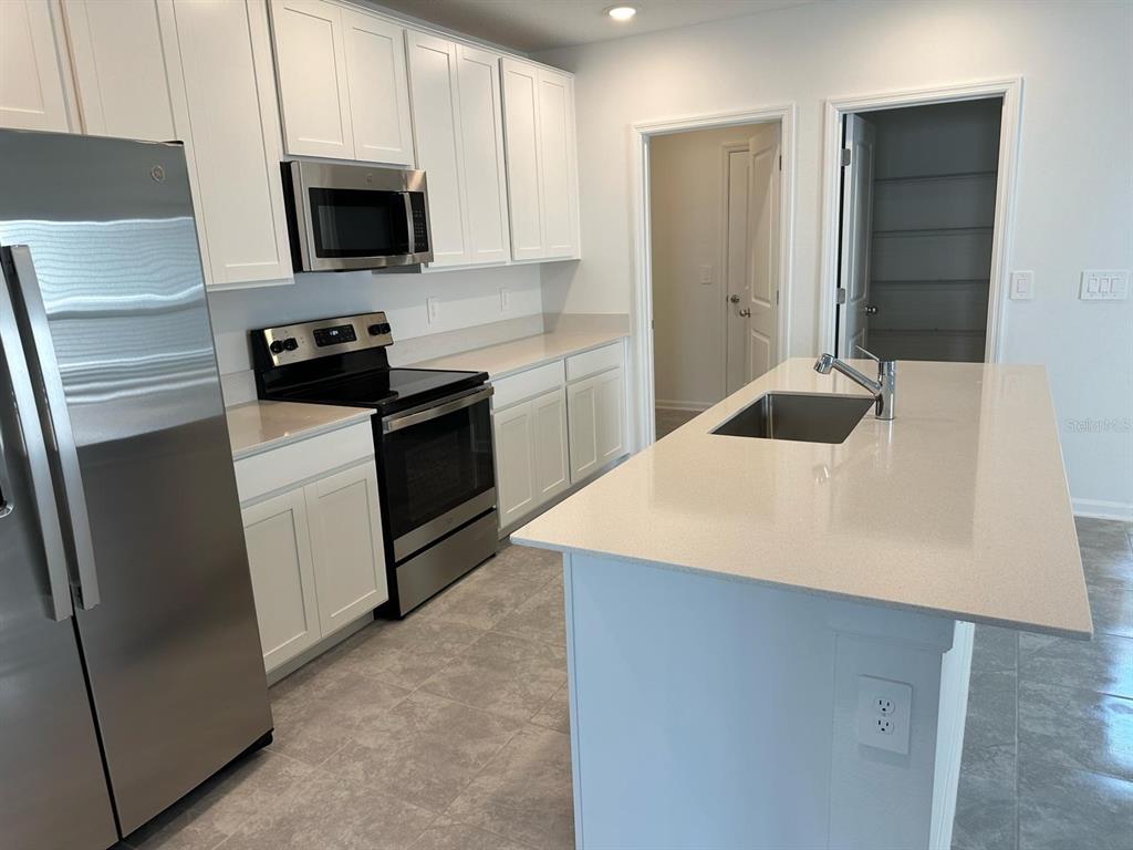 417 Cedar Key Street Davenport, FL 33837 - Photo 4 of 58 a kitchen with a sink a microwave a refrigerator and cabinets