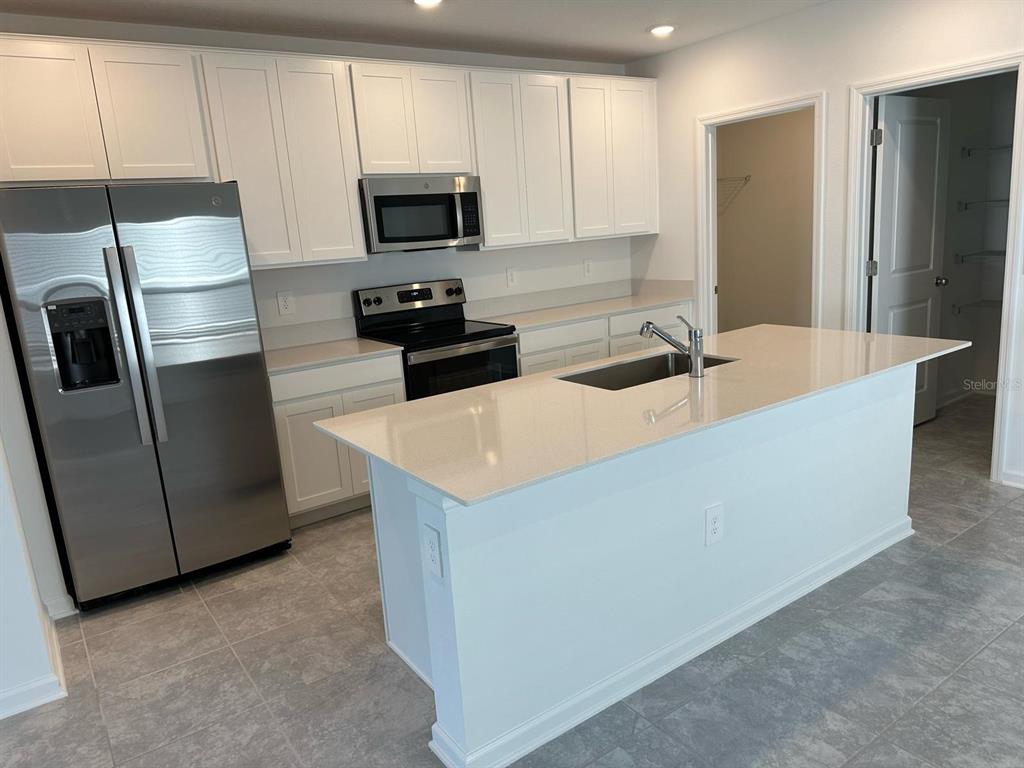 417 Cedar Key Street Davenport, FL 33837 - Photo 43 of 58 a kitchen with stainless steel appliances granite countertop a refrigerator a stove a sink and a refrigerator