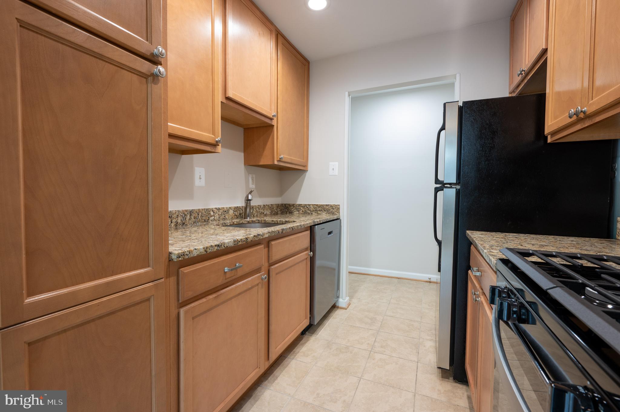 7097 Spring Garden Drive, Unit 101 Springfield, VA 22150 - Photo 2 of 17 a kitchen with stainless steel appliances granite countertop a refrigerator and a stove top oven