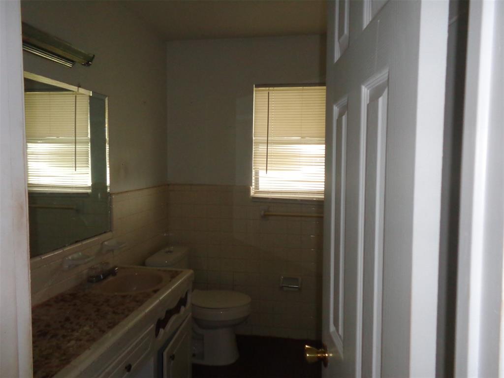 612 South Files Street Itasca, TX 76055 - Photo 20 of 30 Bathroom featuring vanity, tile walls, healthy amount of natural light, and wainscoting
