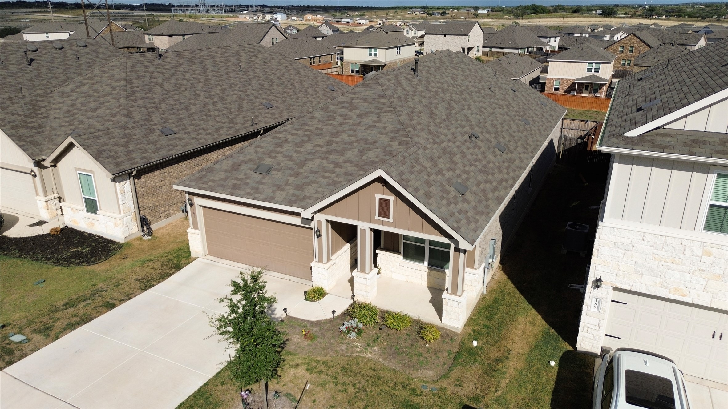 181 Tree Nut Loop Buda, TX 78610 - Photo 27 of 33 An elevated perspective showcases the modern gabled roofline and neat concrete driveway.