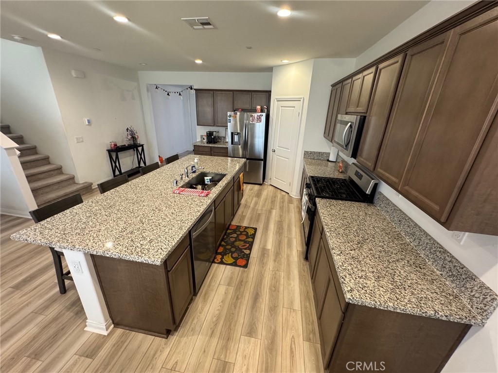 4515 Bandon Avenue Perris, CA 92571 - Photo 5 of 26 a large kitchen with a stove a sink a refrigerator and wooden floor