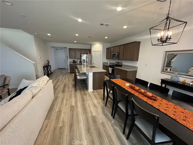 a living room with stainless steel appliances furniture a flat screen tv and kitchen view