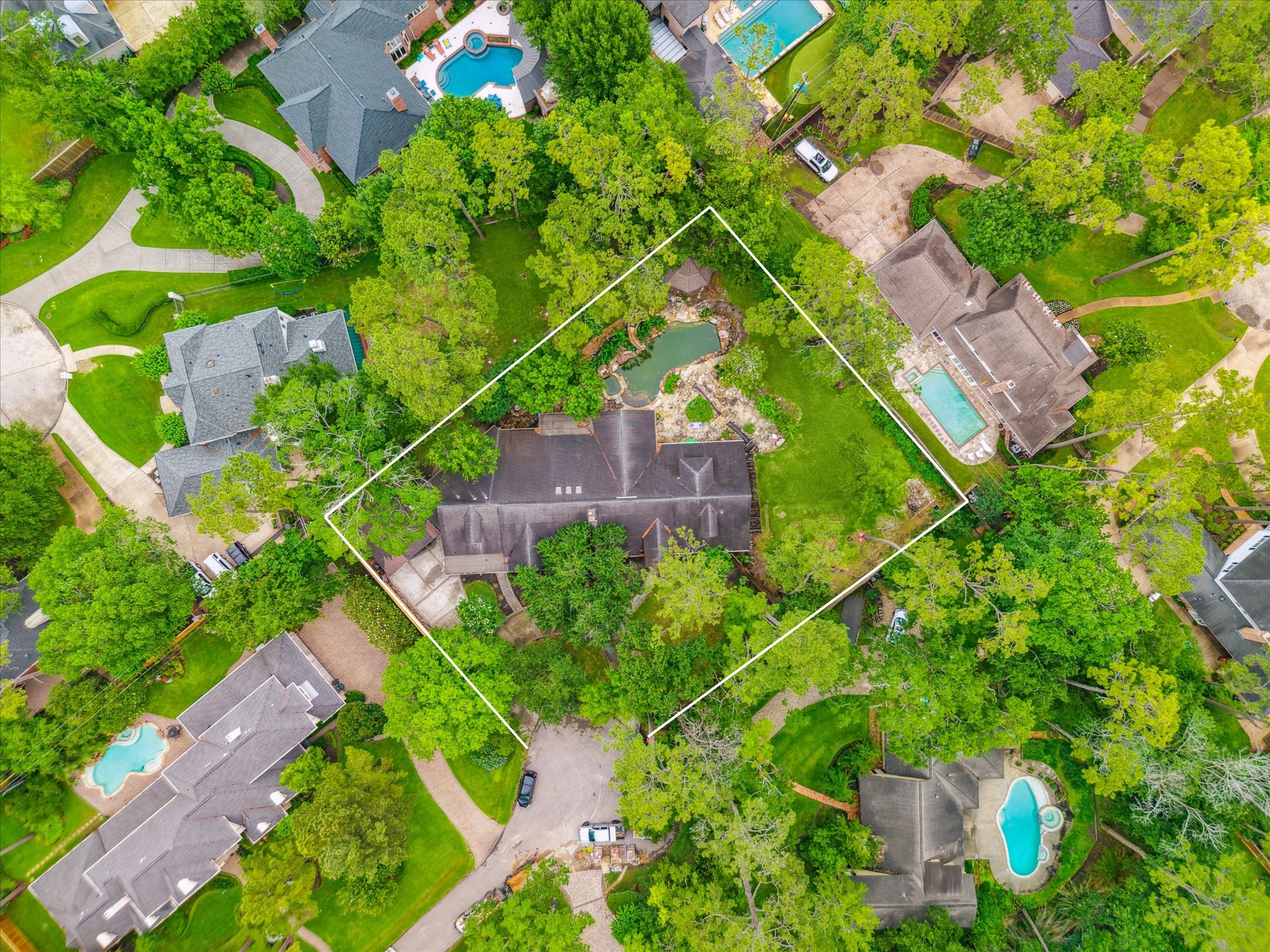 an aerial view of residential house with outdoor space and trees all around