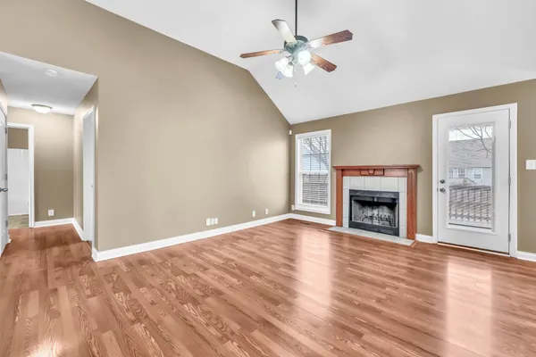an empty room with wooden floor fireplace and windows