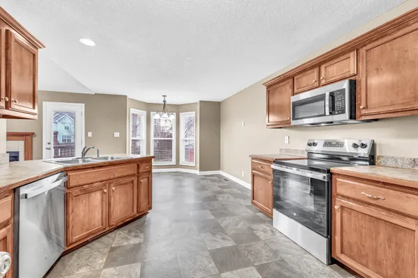 a large kitchen with stainless steel appliances granite countertop a stove sink and cabinets