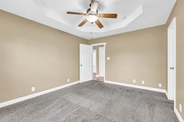a view of an empty room with chandelier fan