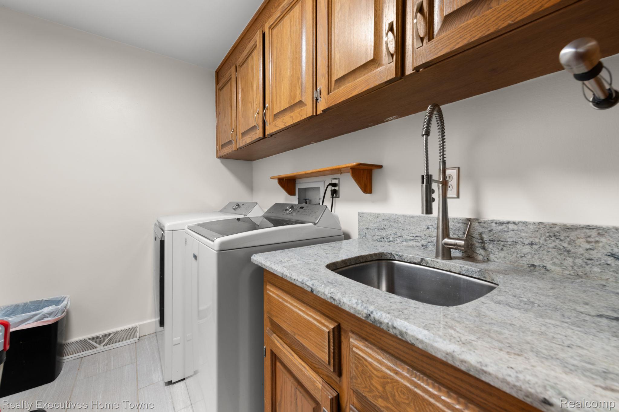 8308 Lakeshore Road Fort Gratiot, MI 48059 - Photo 38 of 79 Utility room featuring light wood cabinetry, a stainless steel sink with a high-arc faucet, and light-toned countertop surfaces