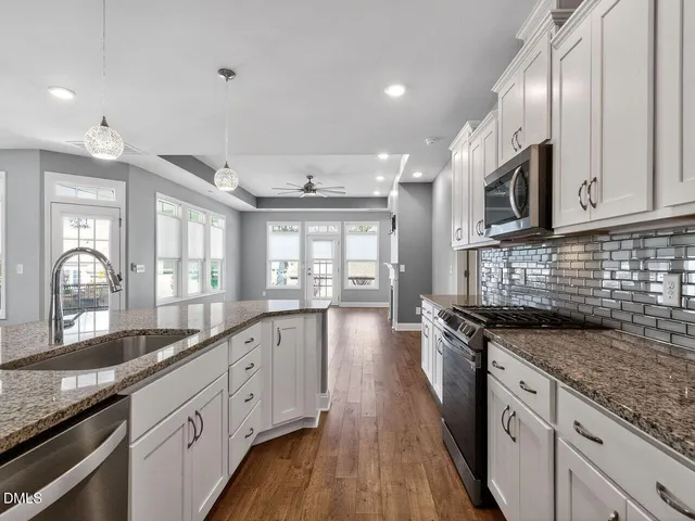 a large kitchen with granite countertop a stove sink and cabinets