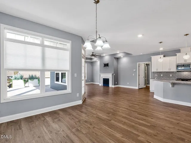 a view of an empty room with kitchen and window