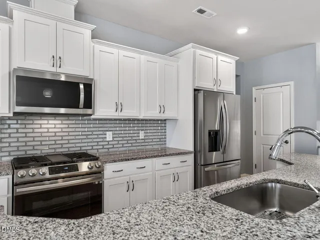 a kitchen with stainless steel appliances granite countertop a sink stove and refrigerator