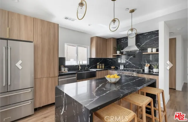 a kitchen with a refrigerator a stove and a kitchen island with wooden floor