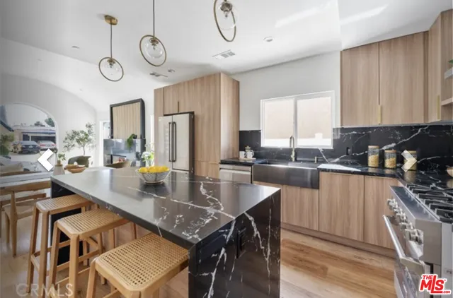 a kitchen with stainless steel appliances granite countertop a stove top oven a sink a dining table and chairs with wooden floor