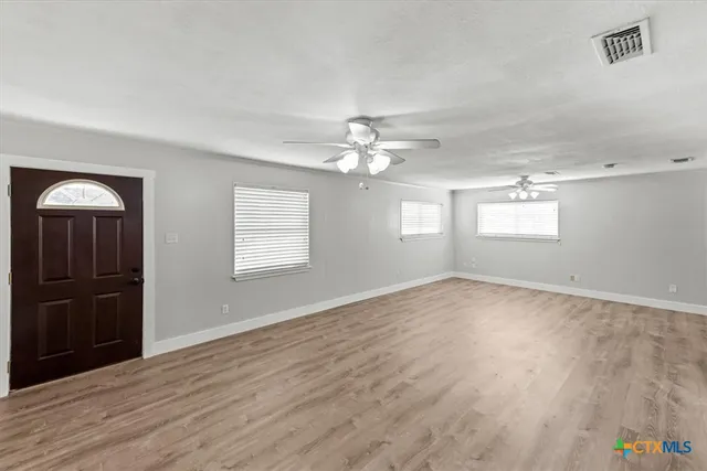 a view of an empty room with a window and wooden floor