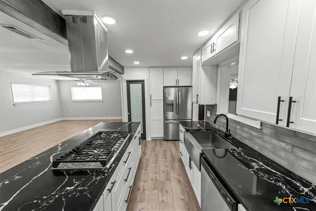 an empty room with wooden floor chandelier fan and windows