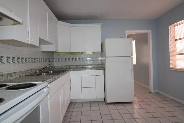 a kitchen with a sink a refrigerator and cabinets