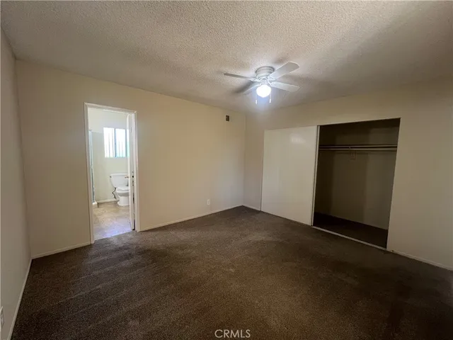 a view of an empty room with a ceiling fan and window