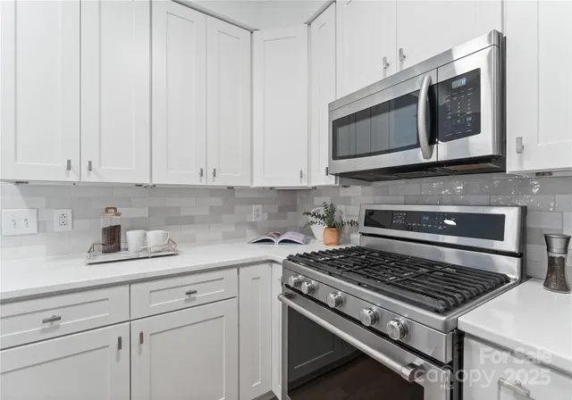 a kitchen with stainless steel appliances granite countertop white cabinets and stove